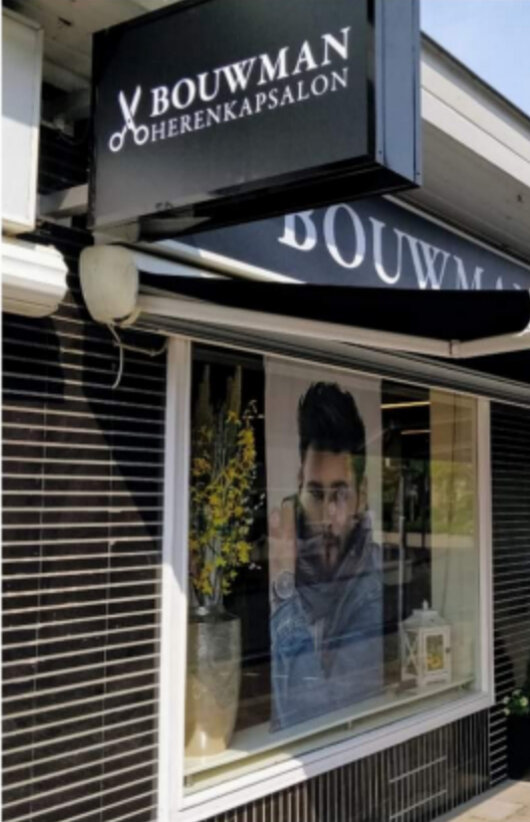 Het uithangbord van Bouwman Herenkapsalon boven de etalage