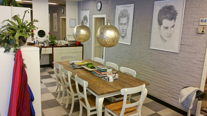 De leestafel in de salon, met tekeningen van herenkapsels aan de muur