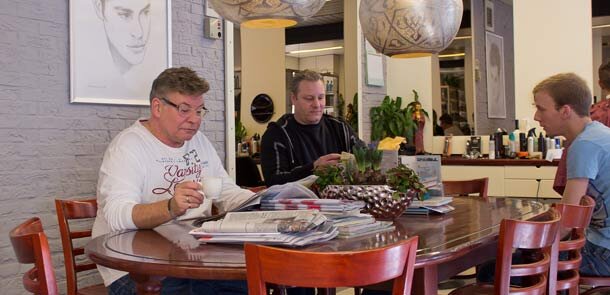 Klanten lezen de krant aan de grote tafel in de salon